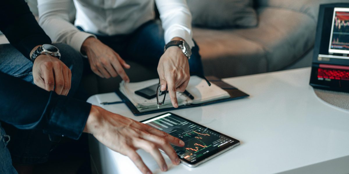 Two businessmen using a tablet to analyze financial data indoors.